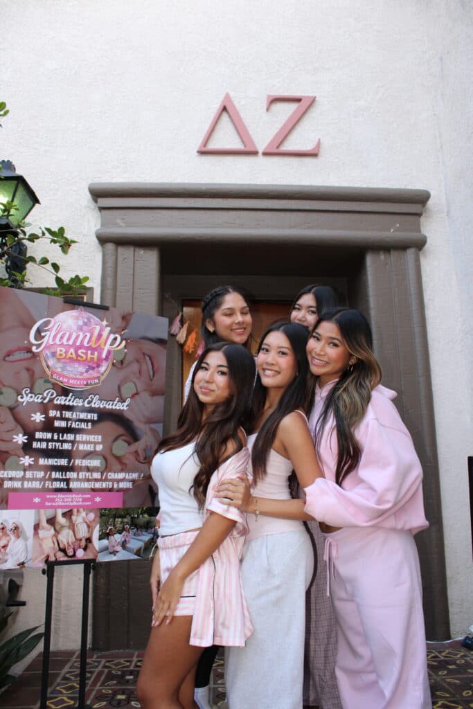 A group dressed in pink robes posing at a GlamUpBash setup.